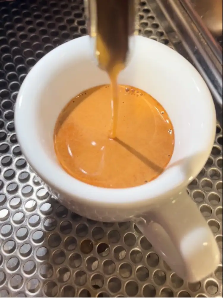 Es läuft Kaffe aus einer Maschine in eine Espressotasse